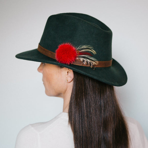 dark green wool felt fedora with tan leather band red fur pom pom and yellow black and brown feathers