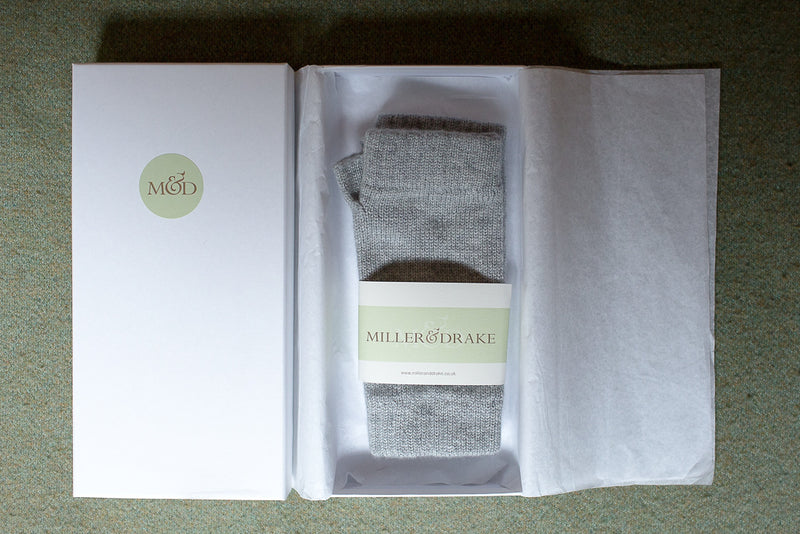 100% cashmere grey wristwarmers wrapped in tissue paper in a luxury white gift box