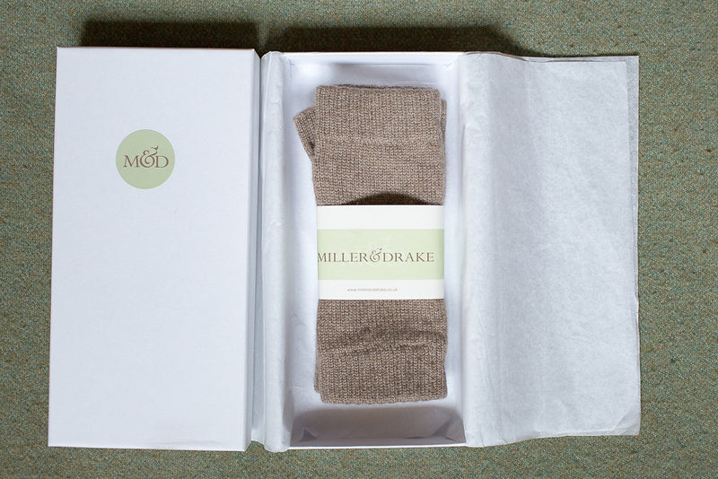 100% cashmere otter beige wristwarmers wrapped in tissue paper in a luxury white gift box