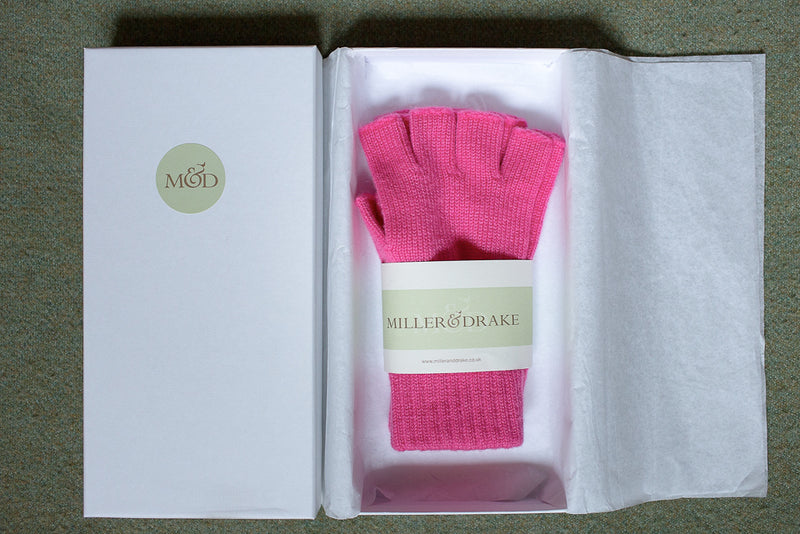 100% cashmere fuchsia pink fingerless gloves wrapped in tissue paper in a luxury white gift box